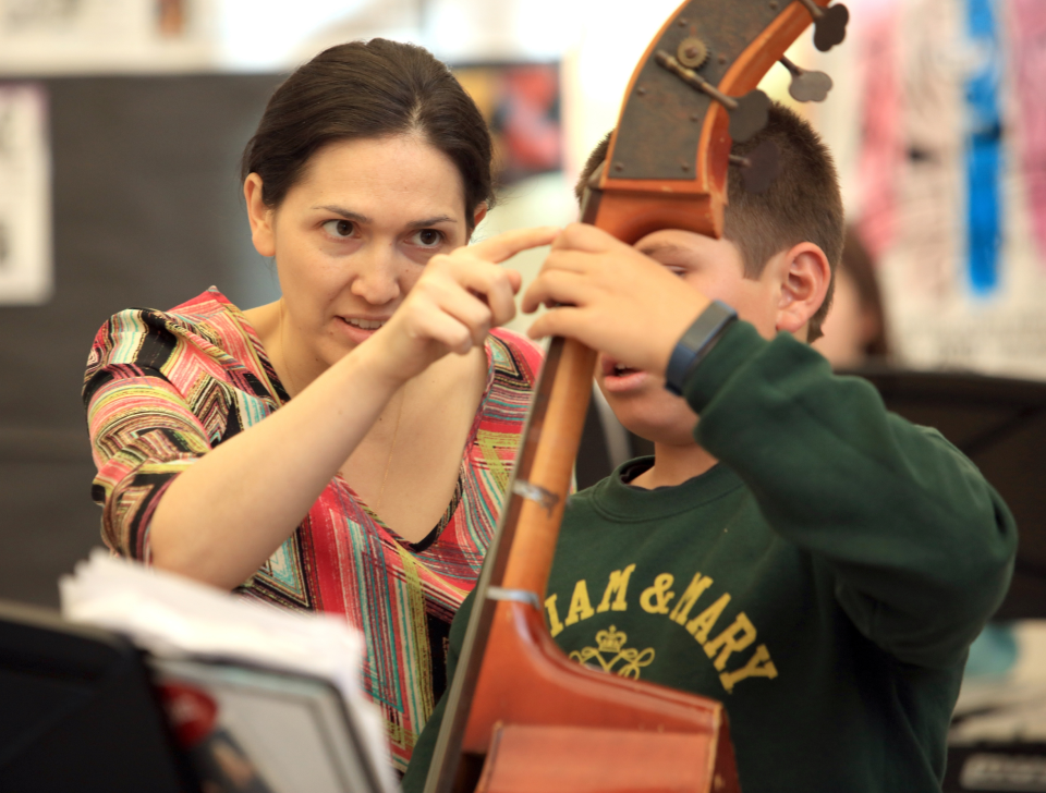 An instructor helping a child learn upright bass