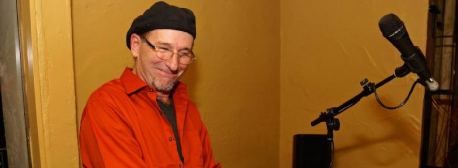 Bill Spencer by a microphone stand in front of a yellow wall