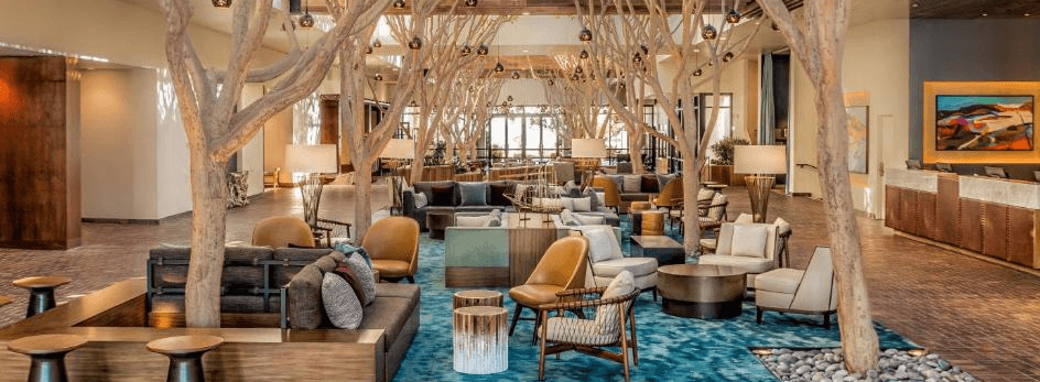 Lobby at Portola Hotel, with couches, chairs and bare trees with hanging lights