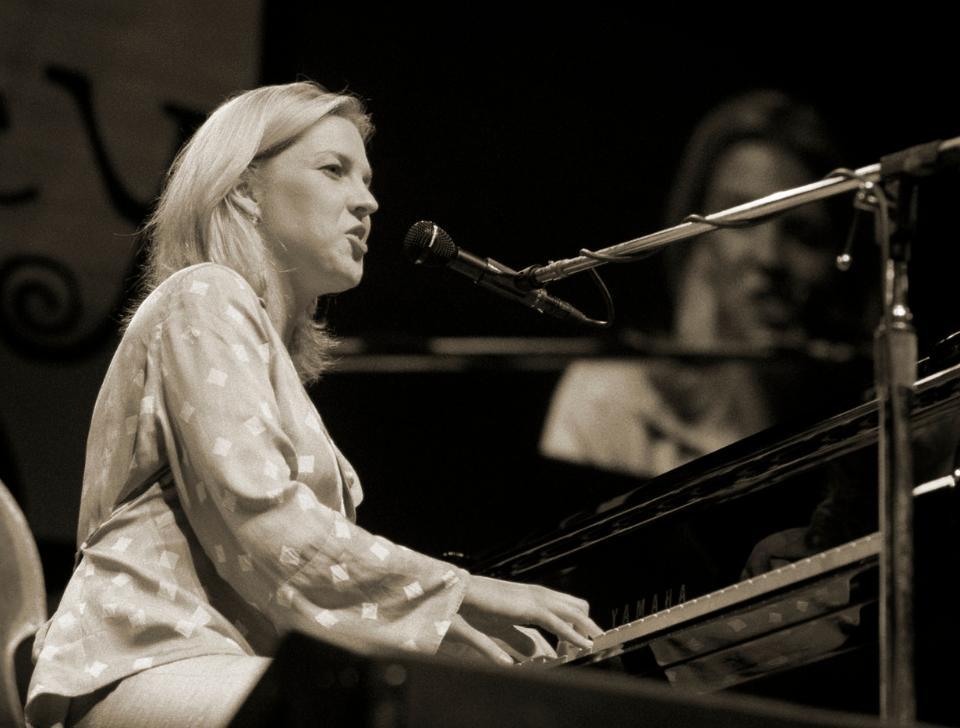 Diana Krall performing on piano and singing, in greyscale