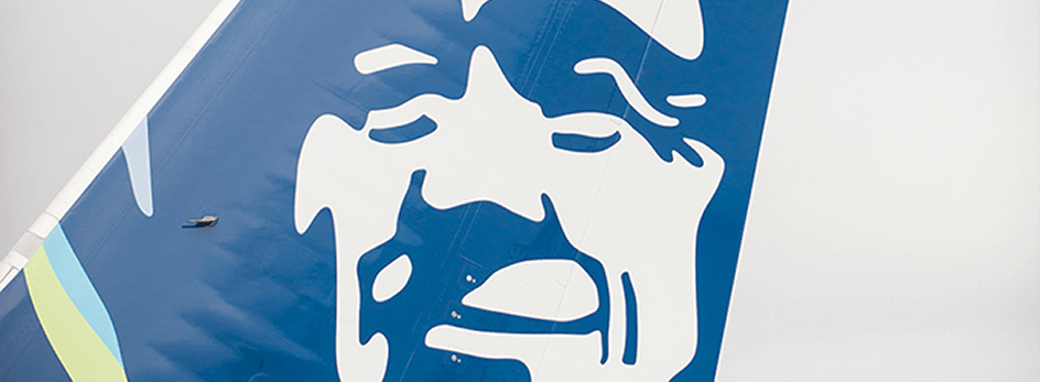 Close up of the tail of an Alaska Airlines aircraft, showing the face of a smiling Inuit man