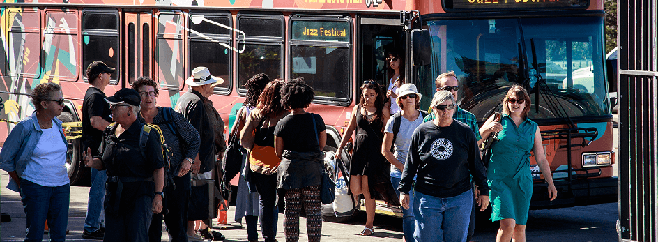 Guests getting off the festival shuttle bus, and more guests waiting to get on.
