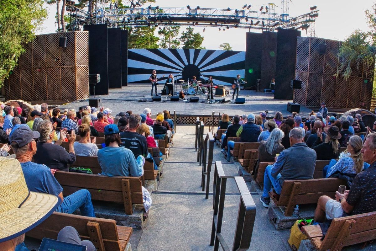 Stage outside with audience members sitting in chairs in front facing the stage.