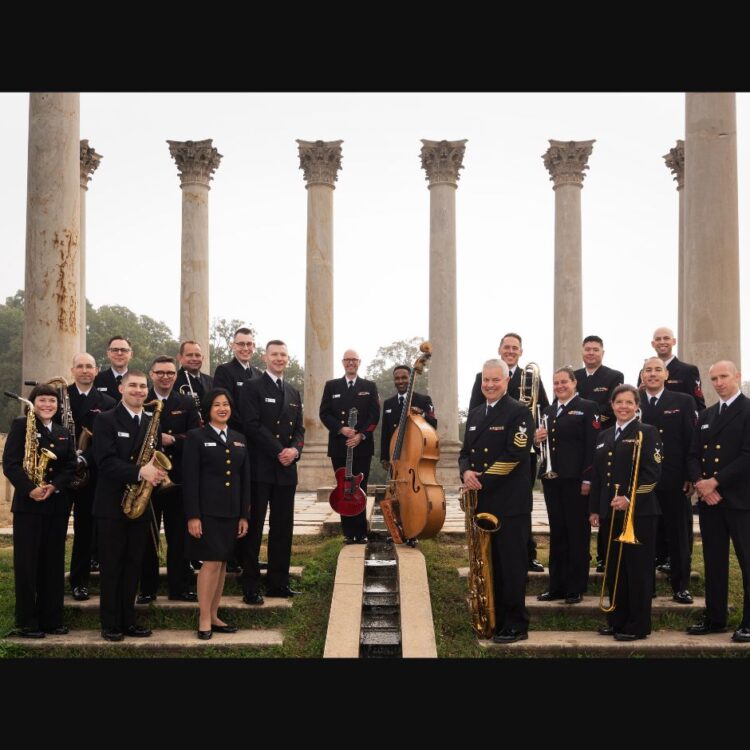 Members of the U.S Navy Band Commodores standing with their instruments surrounded by white pillars
