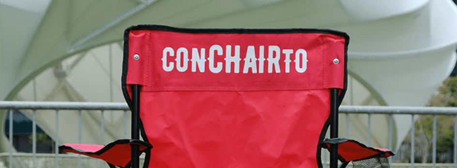 Back of a red folding camp chair that says ConCHAIRto on the back