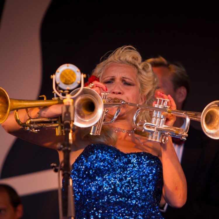 Gunhild Carling performing on stage, playing 3 trumpets at once