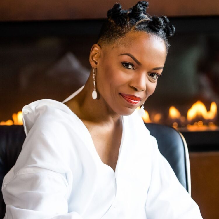 Nnenna Freelon on a leather chair, in front of an out of focus fireplace