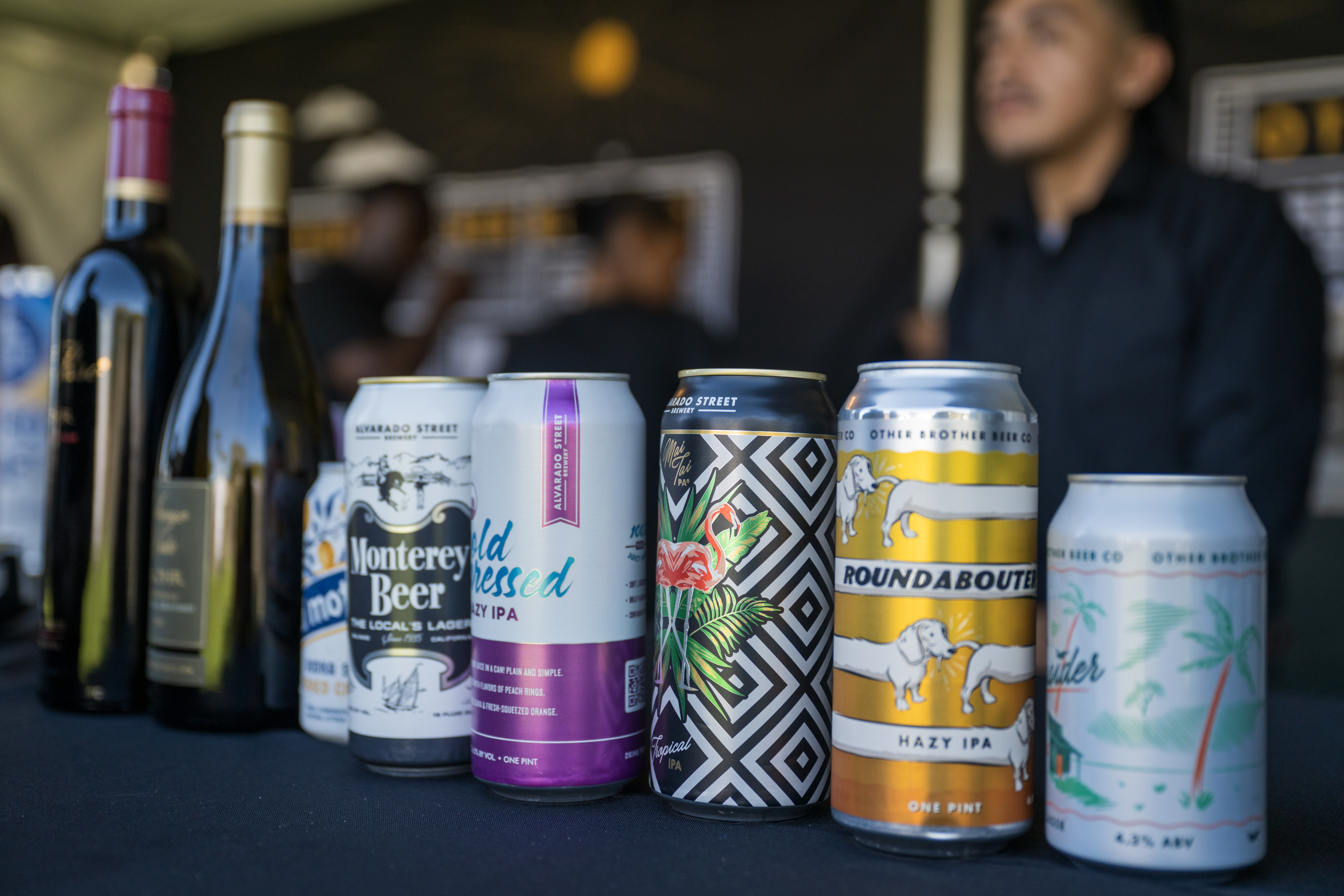 A lineup of beer and wine in front of out of focus bartenders