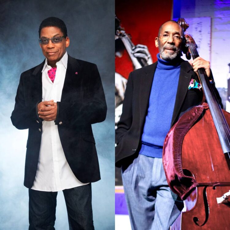 Two men standing, one with a bass