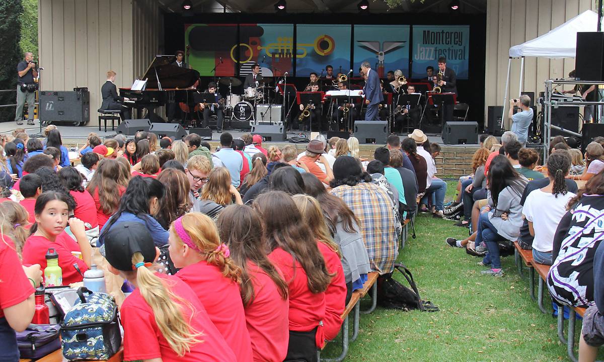 A big band on a stage with sitting students watching them