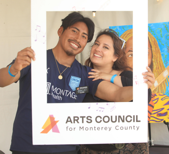 Two people smiling holding a physical picture frame.